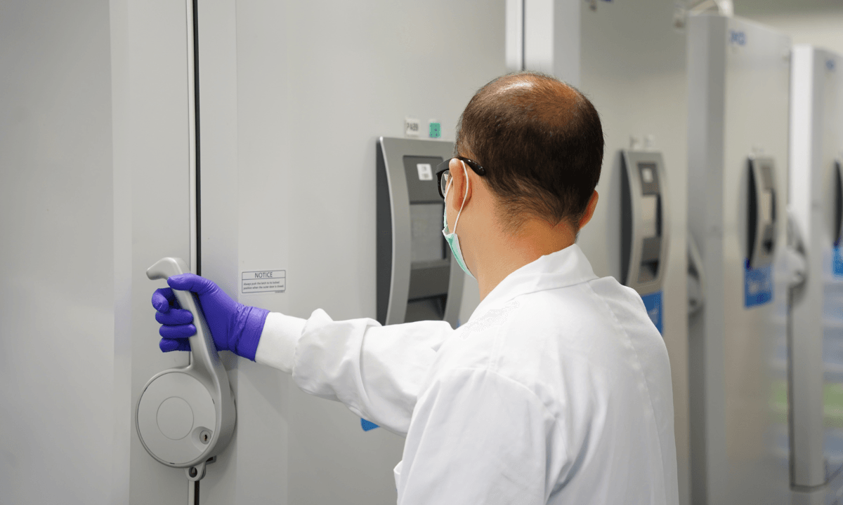 A scientist opening a freezer in a lab.