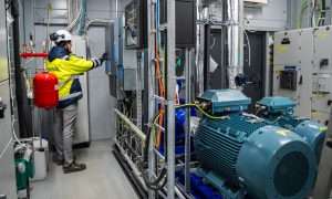 An image of Caverion commissioning the heat pump system in Kajaani. Hydrocarbon heat pumps cool the data center and reuse waste heat for district heating.