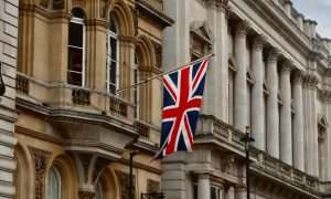 An image of Great Britain's flag against a building backdrop. U.K.'s DEFRA delayed HFC phasedown reform.